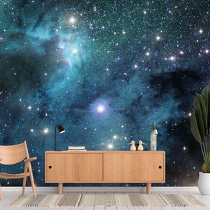 May include: A room featuring a vibrant space-themed wall mural with a wooden cabinet, chair, and potted plant. The mural depicts a nebula with stars in shades of blue and teal. A black desk lamp and decorative items are on the cabinet.