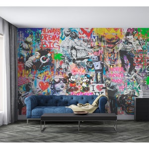 Op de afbeelding: Een grote muurschildering met een levendige graffiti-stijl collage met diverse illustraties waaronder Mickey en Minnie Mouse, een robot, een hond en teksten zoals ALWAYS DREAM BIG en NEVER NEVER EVER GIVE UP, achter een blauwe bank.