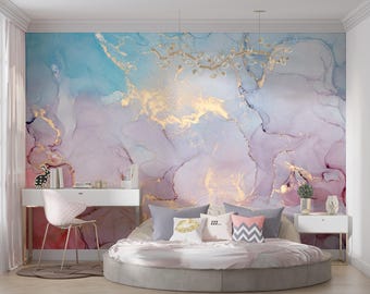 May include: A wall mural featuring an abstract alcohol ink design in shades of light blue, soft pink, and lavender with gold veining. The mural is displayed behind a white desk, a round bed with grey and patterned pillows, and a white nightstand.