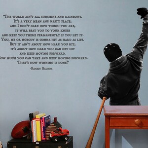 May include: A motivational quote by Rocky Balboa on a blue wall. The quote reads, "The world ain't all sunshine and rainbows. It's a very mean and nasty place, and I don't care how tough you are, it will beat you to your knees and keep you there permanently if you let it. You, me or nobody is gonna hit as hard as life. But it ain't about how hard you hit, it's about how hard you can get hit and keep moving forward. How much you can take and keep moving forward. That's how winning is done!" -Rocky Balboa