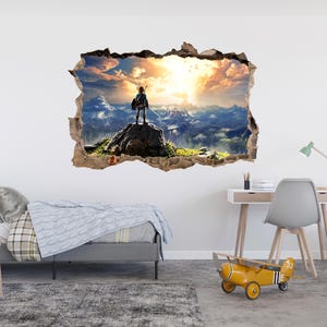 Puede incluir: Un adhesivo de pared con efecto 3D que muestra un agujero en la pared revelando un paisaje. Una figura se encuentra sobre una roca frente a una cordillera bajo un cielo de atardecer dorado con nubes. El dise&ntilde;o tiene bordes de papel rasgado.