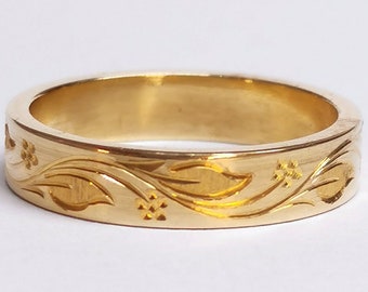 May include: A gold band ring with a floral design engraved on the surface.
