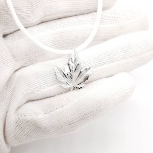 May include: A silver maple leaf pendant necklace on a white cord.