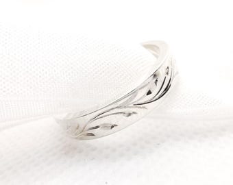 May include: A silver ring with a delicate floral design. The ring is made of metal and has a smooth, polished finish.