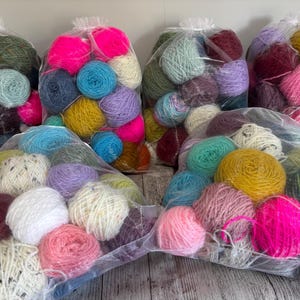 May include: Six transparent organza drawstring bags filled with assorted yarn balls in a wide variety of colours including neon pink, mustard yellow, sky blue, white, lavender, forest green, and deep burgundy, showcasing various textures and weights.
