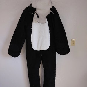 Puede incluir: Mono de peluche negro y blanco con capucha. El mono tiene una cara blanca con ojos negros y una nariz negra.