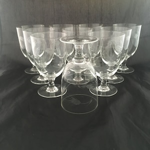May include: A set of ten clear glass goblets with a delicate etched wheat design. The goblets have a round bowl and a tall, slender stem.