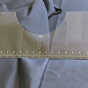 May include: A clear plastic sewing ruler with a curved edge and a ruler marked in inches from 0 to 9 on each side.