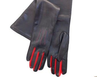 May include: A pair of long black leather gloves with red stitching and red leather trim on the fingertips.
