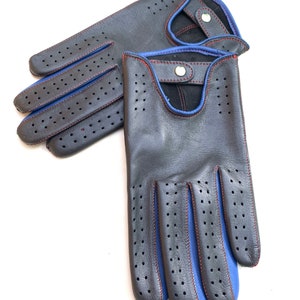 May include: A pair of black leather driving gloves with blue stitching and red stitching detail. The gloves have a perforated design and a snap closure.