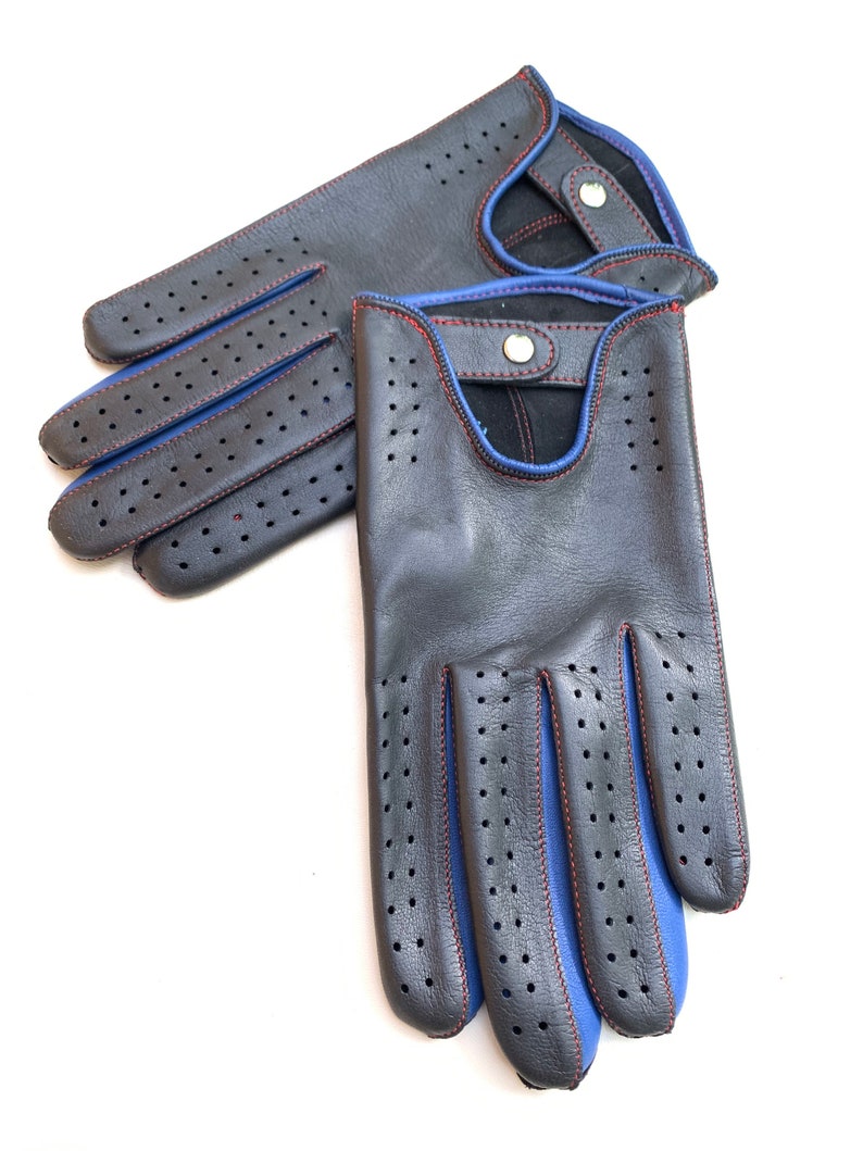 May include: A pair of black leather driving gloves with blue stitching and red stitching detail. The gloves have a perforated design and a snap closure.