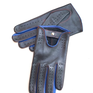 May include: A pair of black leather driving gloves with blue and red stitching. The gloves have a perforated design and a snap closure.