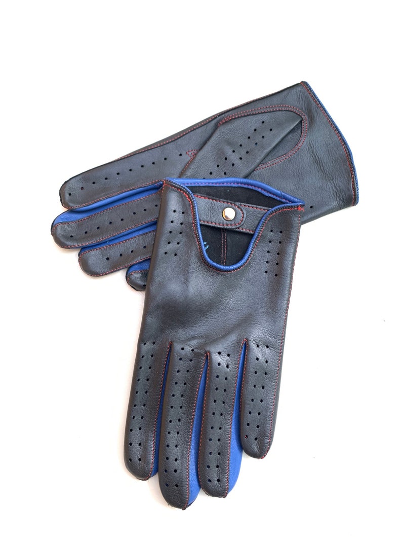 May include: A pair of black leather driving gloves with blue and red stitching. The gloves have a perforated design and a snap closure.