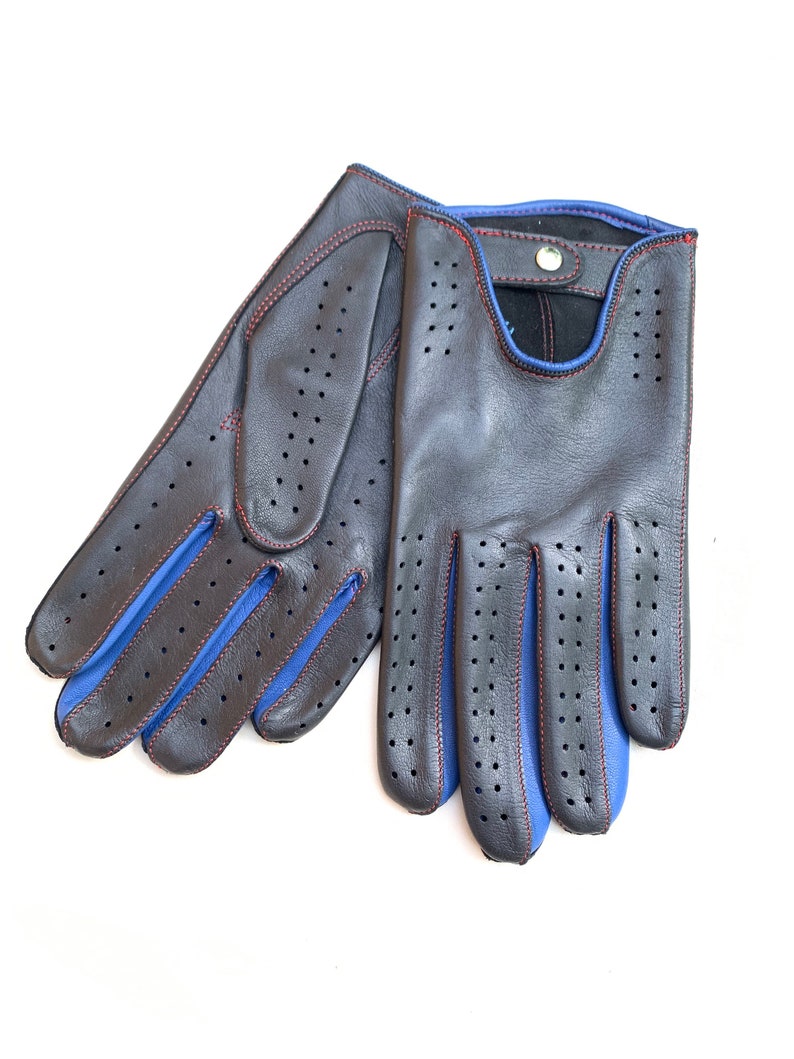 May include: A pair of black leather driving gloves with blue trim and red stitching. The gloves have a perforated design and a button closure.