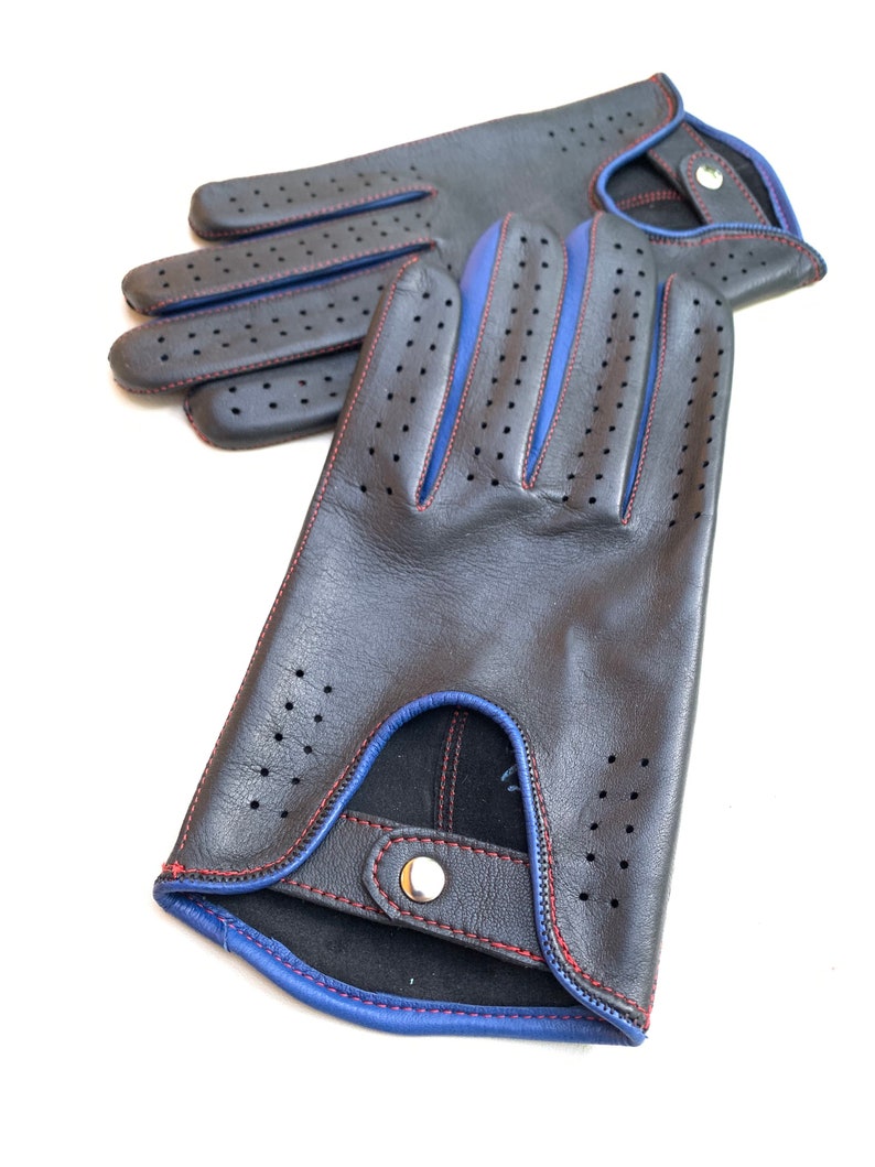 May include: A pair of black leather driving gloves with blue and red stitching. The gloves have a perforated design and a snap closure.