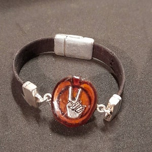 Unique bracelet made of dark brown cork with peace sign in a branch disc poured with epoxy.