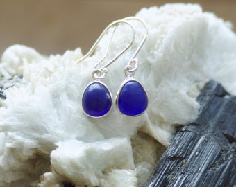 May include: A pair of silver dangle earrings with dark blue teardrop-shaped glass stones.