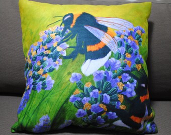 May include: A decorative square pillow featuring a detailed illustration of a bumblebee on lavender flowers. The bee has black and orange stripes, with white accents. The background is a bright green, with purple and gold flowers.