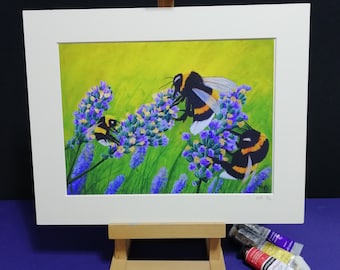 May include: A framed painting of bumblebees on lavender flowers. The artwork features three bees with black and yellow stripes, set against a green and purple background. The painting is displayed on a small wooden easel, with paint tubes and brushes nearby.