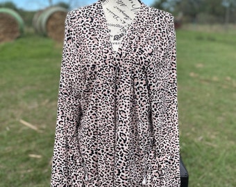 May include: A long-sleeved blouse with a pink and black leopard print pattern. The blouse has a V-neck and a relaxed fit.
