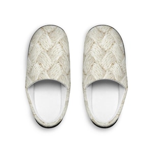 May include: A pair of cream-colored slippers with a woven cable knit pattern. The interior is white, and the soles are black. The slippers are designed for indoor use and provide comfort and warmth.