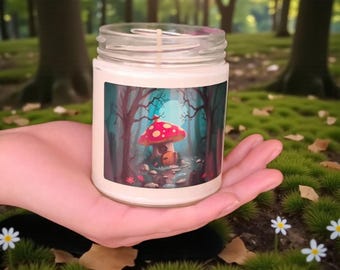 May include: A glass jar candle with a whimsical forest scene label. The label features a red mushroom house with white spots, set in a mystical forest with a path. The candle is held in a hand, surrounded by greenery.