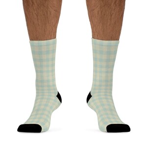 Könnte beinhalten: Ein Paar Socken mit hellblauem und cremefarbenem Karomuster. Die Socken haben schwarze Fersen und Zehen. Die Socken werden an den Beinen einer Person getragen.