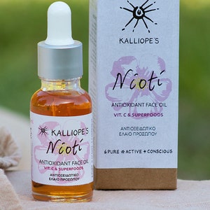 Może przedstawiać: Szklana butelka z olejkiem do twarzy Niotí Antioxidant Face Oil z witaminą C i superfoods marki Kalliope's. Butelka jest w kolorze bursztynowym i ma srebrną pipetę. Etykieta jest biała z czarnym tekstem i grafiką różowego kwiatu. Butelka stoi na beżowej powierzchni z tkaniny.