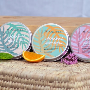May include: Three 100ml tin containers of herbal body lotion with a light blue, light green, and pink background. The containers are labelled "KALLIOPE'S Herbal Body Lotion" with the text "PURE ACTIVE + CONSCIOUS" on the side. The containers are sitting on a woven wicker surface.