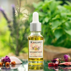 The nioti antioxidant face oil, in a glass 20ml bottle with a dropper. Its colour is bright orange thanks to carotenoids. The backround islush green foliage and it's surounded by pomegranate fruits, seabuckthorn berries and roses.