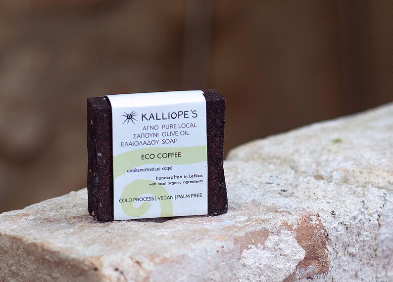 Może przedstawiać: Brązowe mydło z białą etykietą, na kt&oacute;rej widnieje napis "KALLIOPE'S AGNO PURE LOCAL SAPOUNI OLIVE OIL ELAIOLADOU SOAP ECO COFFEE &alpha;&pi;&omicron;&lambda;&epsilon;&pi;&iota;&sigma;&tau;&iota;&kappa;ό &mu;&epsilon; &kappa;&alpha;&phi;έ handcrafted in Lefkas with tocol orgonic ingredients COLD PROCESS | VEGAN | PALM FREE".