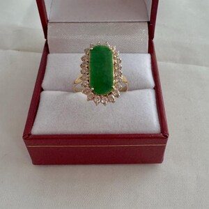 May include: A gold ring with a large green jade stone surrounded by a halo of small diamonds.