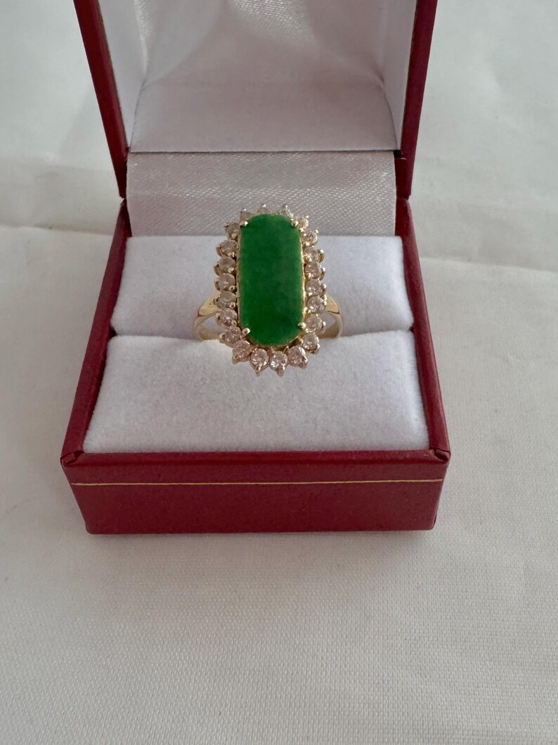 May include: A gold ring with a large green jade stone surrounded by a halo of small diamonds.