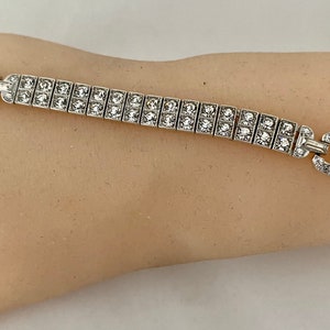 May include: A silver bracelet with a row of clear square-shaped stones.