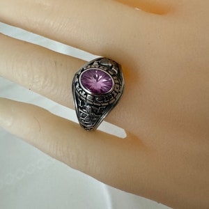May include: A silver class ring with a purple stone and engraved details.