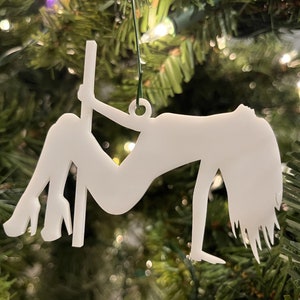 Könnte beinhalten: Weißer Silhouetten-Weihnachtsbaumschmuck einer Person, die an einem Pfosten hängt. Der Schmuck hängt an einem grünen Weihnachtsbaum.