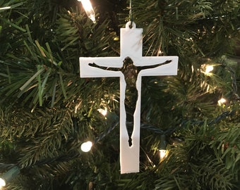 Könnte beinhalten: Weißer Weihnachtsbaumschmuck aus Kunststoff in Form eines Kreuzes mit einem Ausschnitt einer Person auf dem Kreuz.