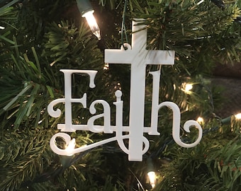 Könnte beinhalten: Weißer Weihnachtsbaumschmuck mit dem Wort "Glaube" und einem Kreuzdesign.