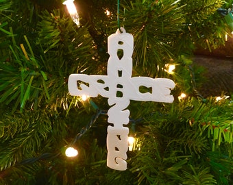 Könnte beinhalten: Weißer Weihnachtsbaumschmuck in Form eines Kreuzes mit dem Wort "GRACE" darauf.