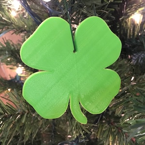 May include: A green four-leaf clover ornament hanging on a Christmas tree.
