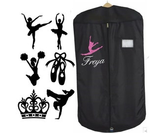 May include: Black garment bag with a zipper closure and a clear plastic window. The bag has a pink glitter design of a dancer and the name "Freya" embroidered on it. The image also includes several black silhouette images of dancers, a crown, and a cheerleader.