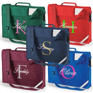 May include: Five personalised school satchels in green, red, navy, burgundy, and blue. Each bag has a name embroidered in a contrasting colour. The bags have a top handle, a shoulder strap, and a reflective stripe.