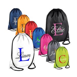 May include: Assortment of drawstring bags in various colours with personalised names and initial letters. The bags are made of a lightweight fabric and have a simple design.