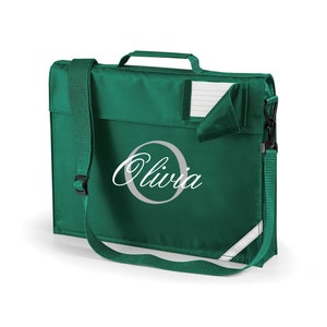 Pu&ograve; includere: Uno zaino verde con una tracolla regolabile bianca e un nome bianco, "Olivia", in un cerchio. Lo zaino ha una piccola tasca sul davanti con una patta bianca.