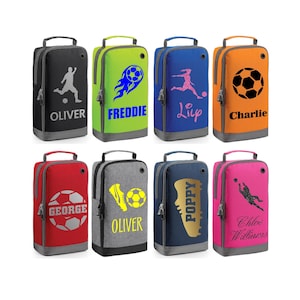 May include: A collection of eight personalised football boot bags in different colours, including black, green, blue, and orange. Each bag has a football graphic and a name, such as "Oliver" or "Charlie". The bags have a handle and a zip.
