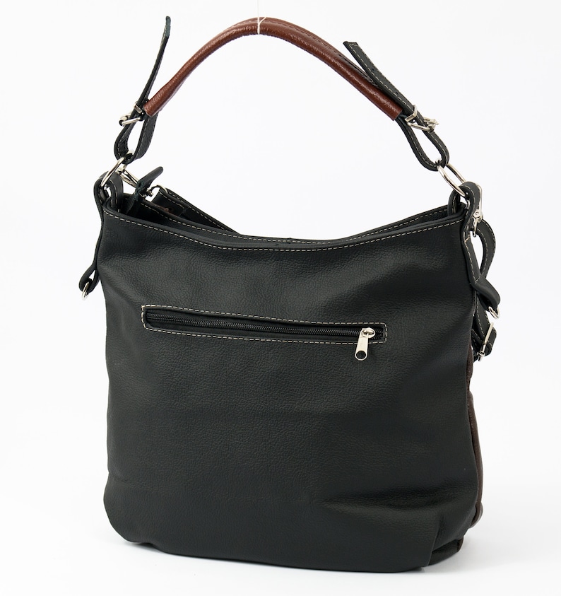 Pode incluir: Uma bolsa de m&atilde;o de couro preto com al&ccedil;a de couro marrom e ferragens prateadas. A bolsa tem um bolso com z&iacute;per na frente e um fecho de aba.