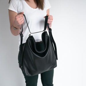 Pode incluir: Uma mochila conversível de couro preto com alças ajustáveis. A mochila tem um compartimento principal grande e um bolso frontal menor.