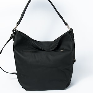 May include: Black leather shoulder bag with a zippered pocket on the front and a long adjustable strap.