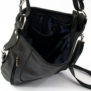 May include: A black leather shoulder bag with a zippered closure and a long adjustable strap. The bag has a flap with a magnetic closure and a small pocket on the front.