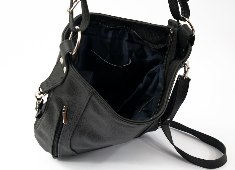 May include: A black leather shoulder bag with a zippered closure and a long adjustable strap. The bag has a flap with a magnetic closure and a small pocket on the front.